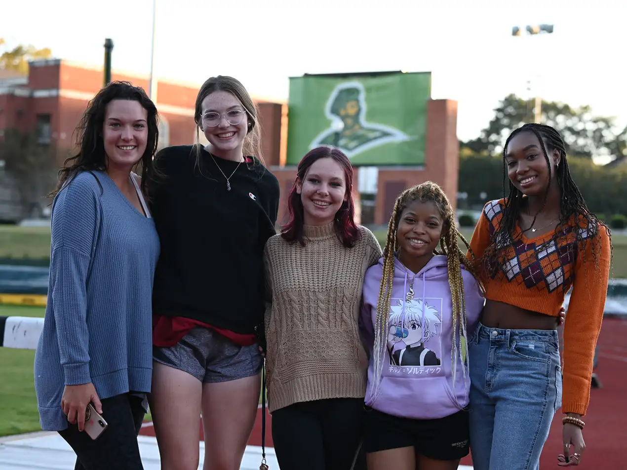 five students smiling in front of the Belhaven bowl