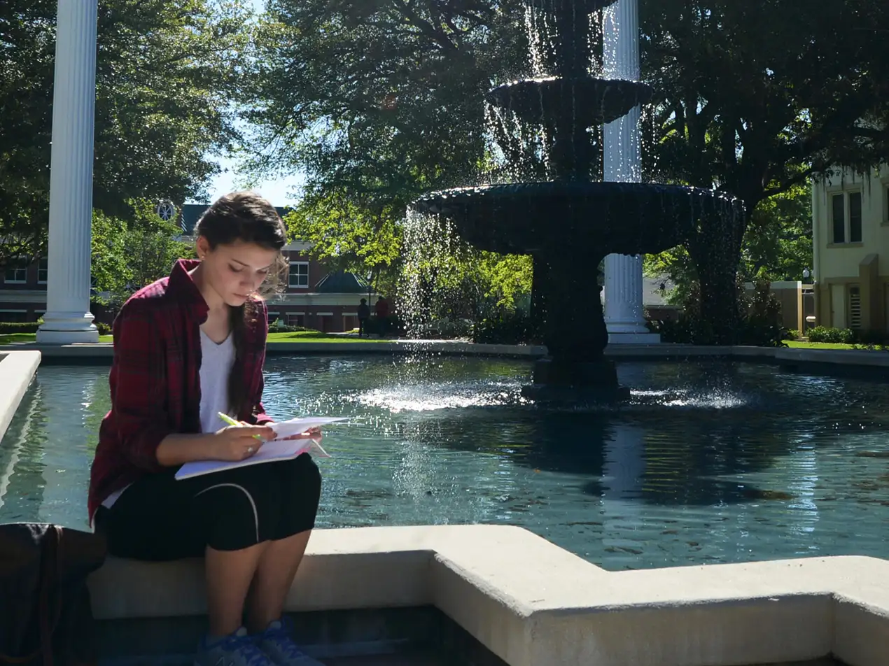 student reading beside the fountain