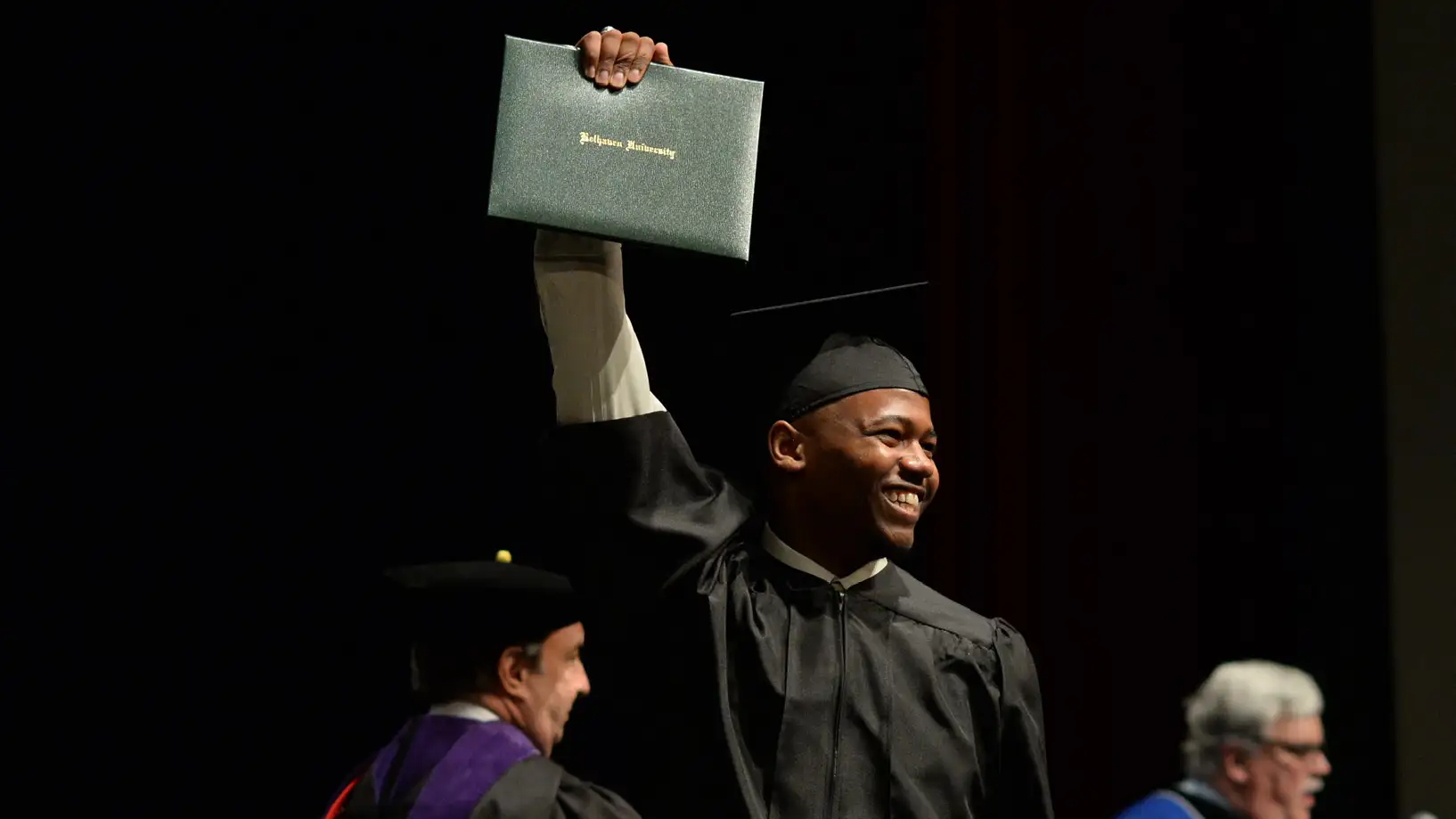 graduate holding his diploma high