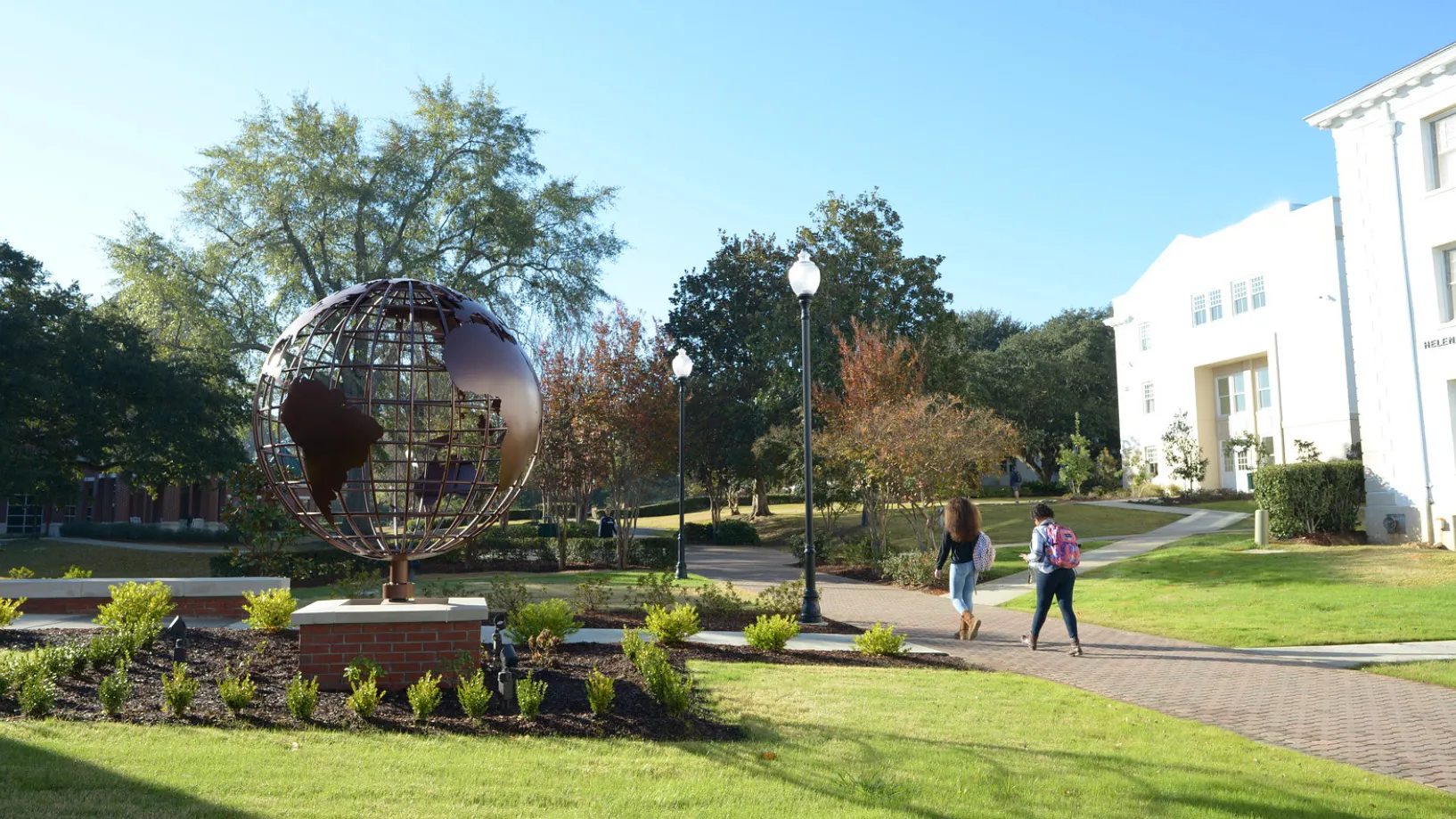 students walking near the globe in front of the Dr. Billy Kim International Center