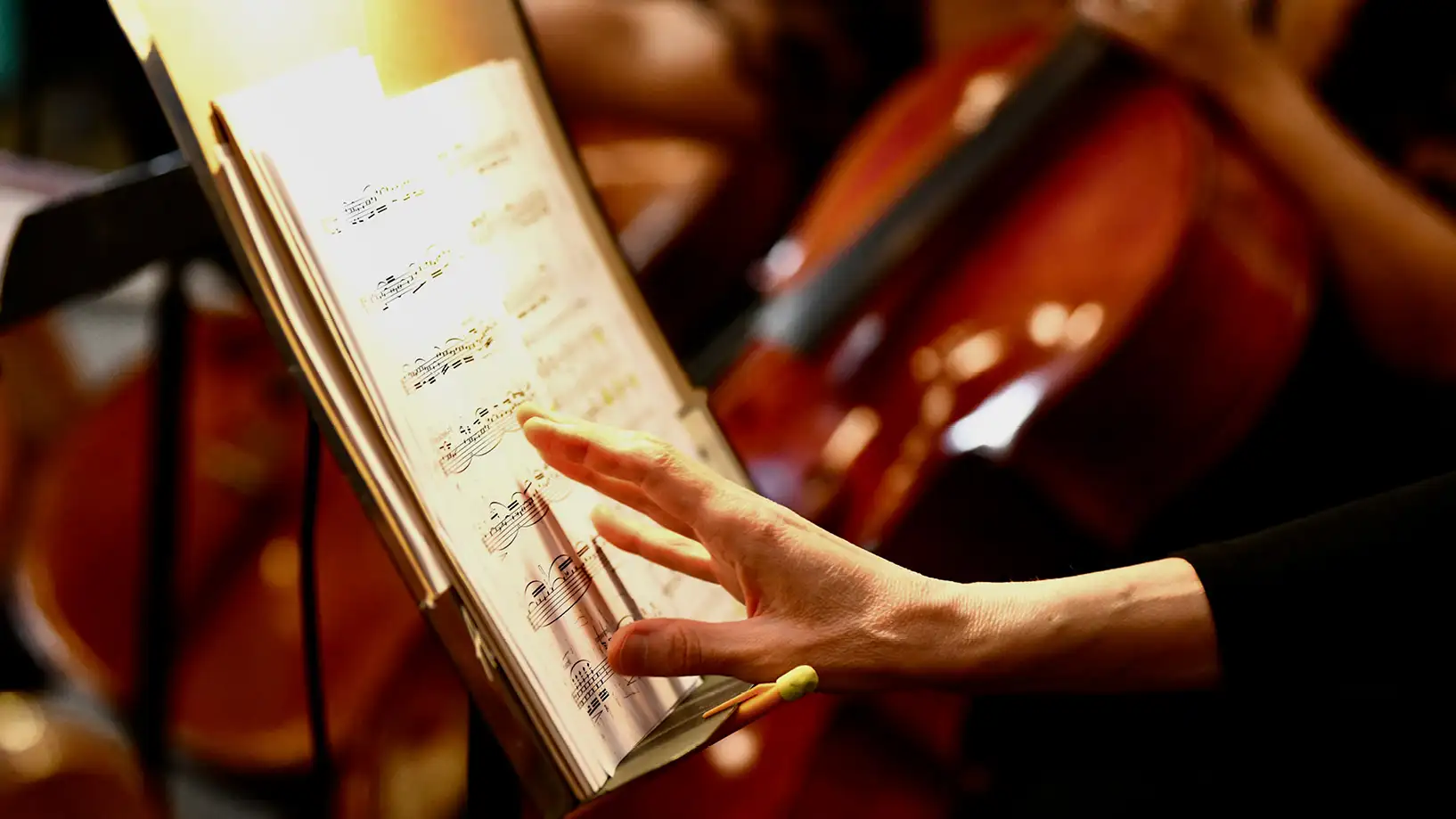 upclose view of sheet music, chello in the background