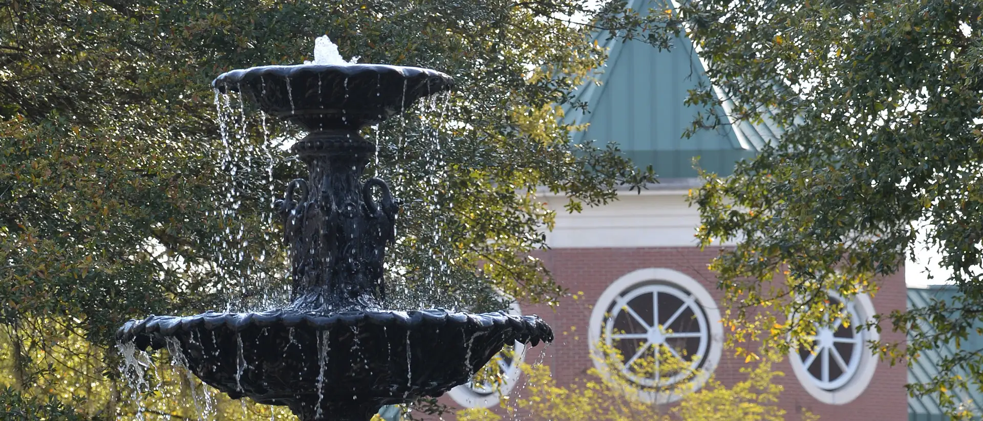 the fountain splashing with student center in the background, trees on the side