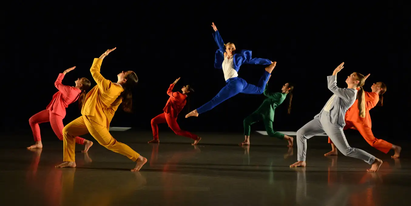Behaven dancers in a performance all wearing colorful costumes