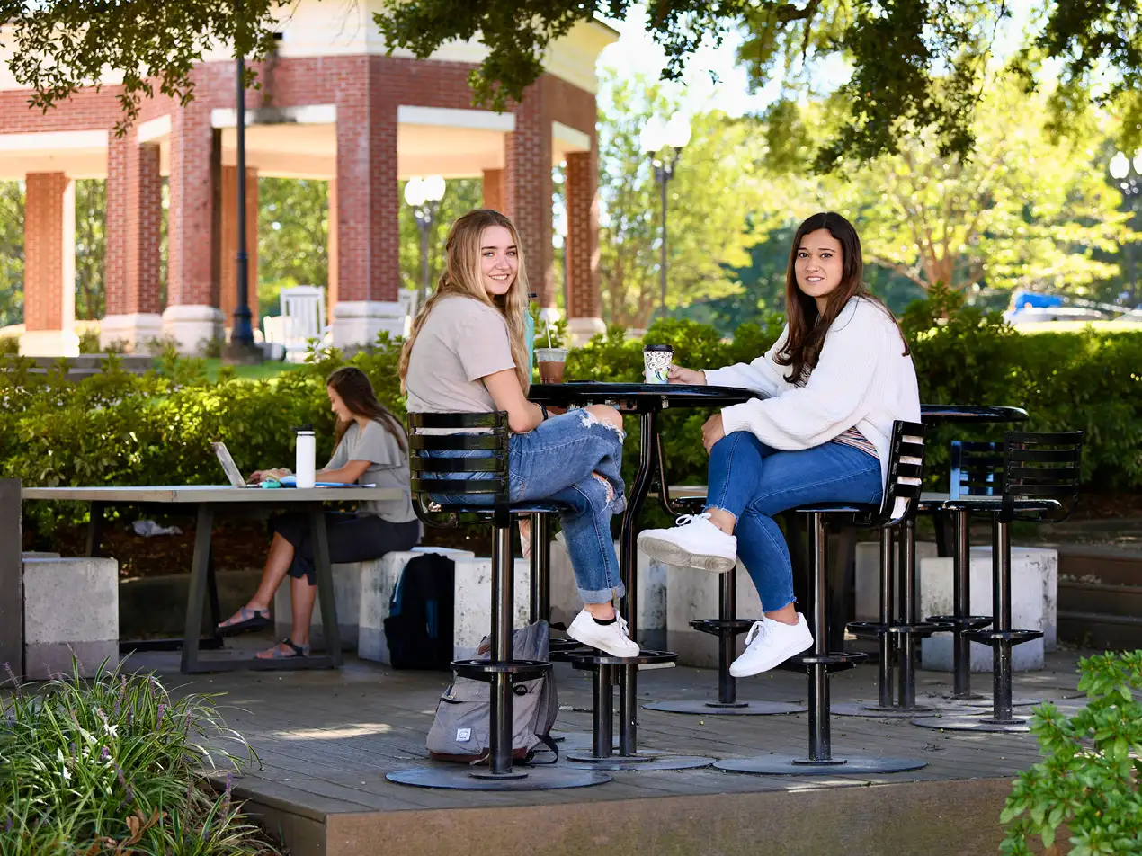 two students visiting outside over coffee