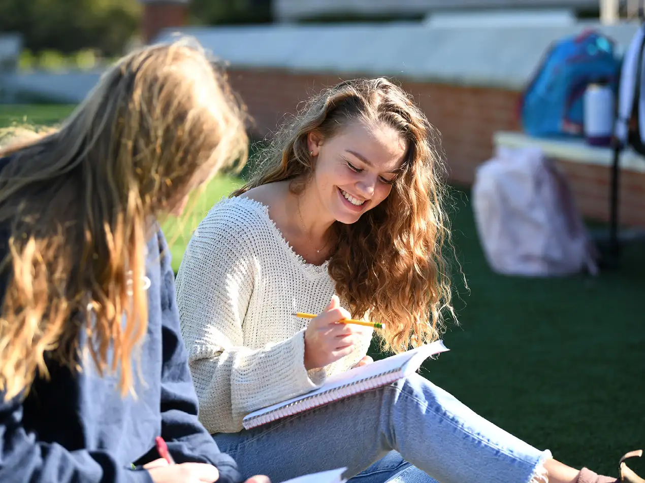 two student studying on the lawn
