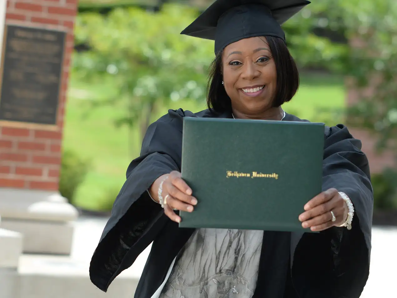 adult student holding diploma while smiling