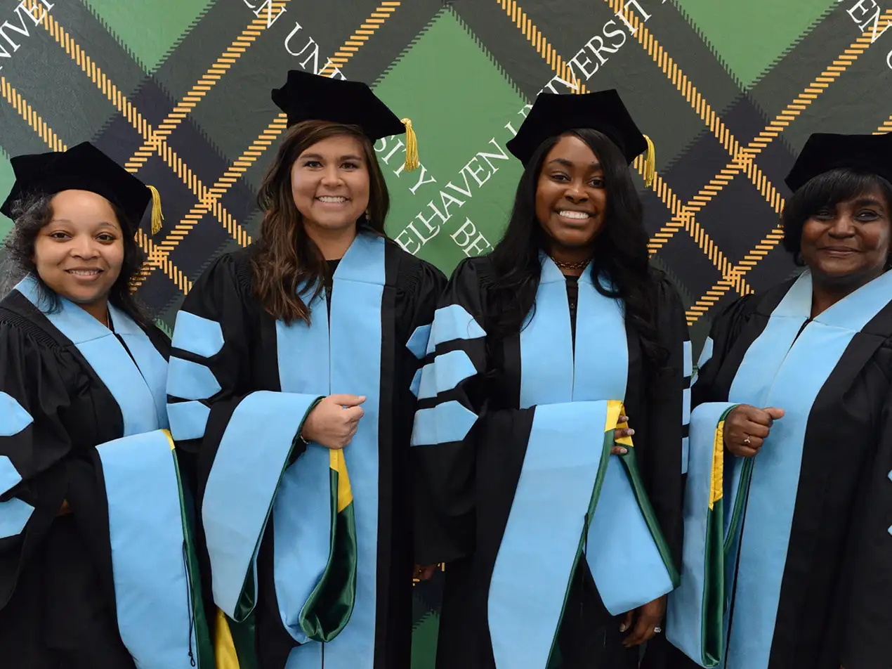 four students in doctoral regalia
