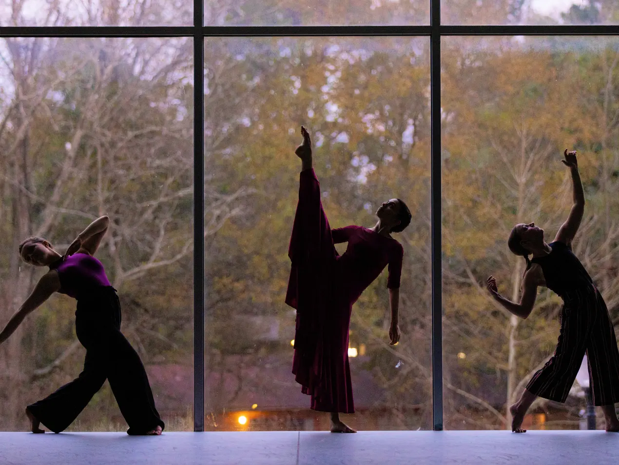three dancers in front of a large window