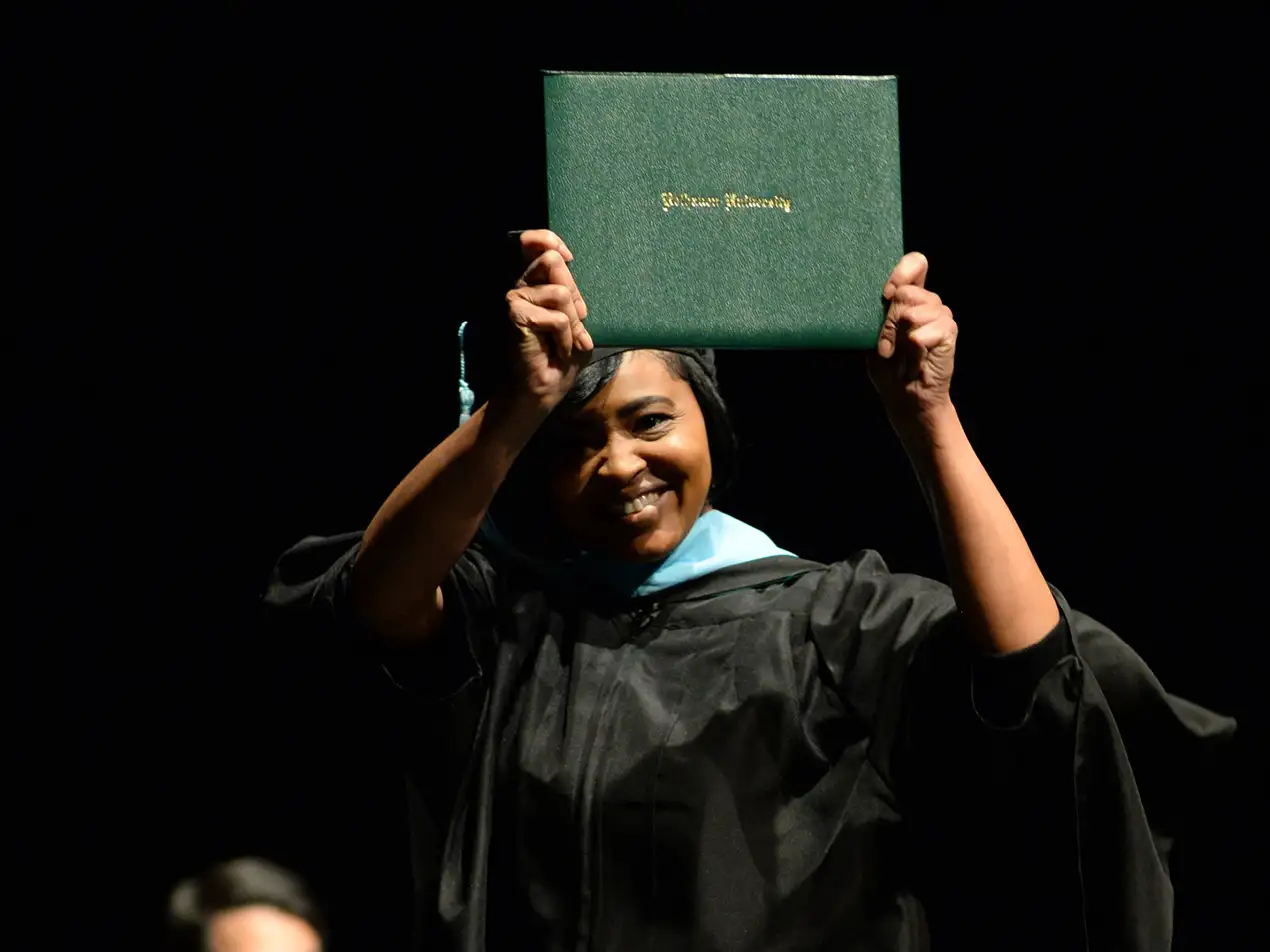 graduate walking across stage with diploma