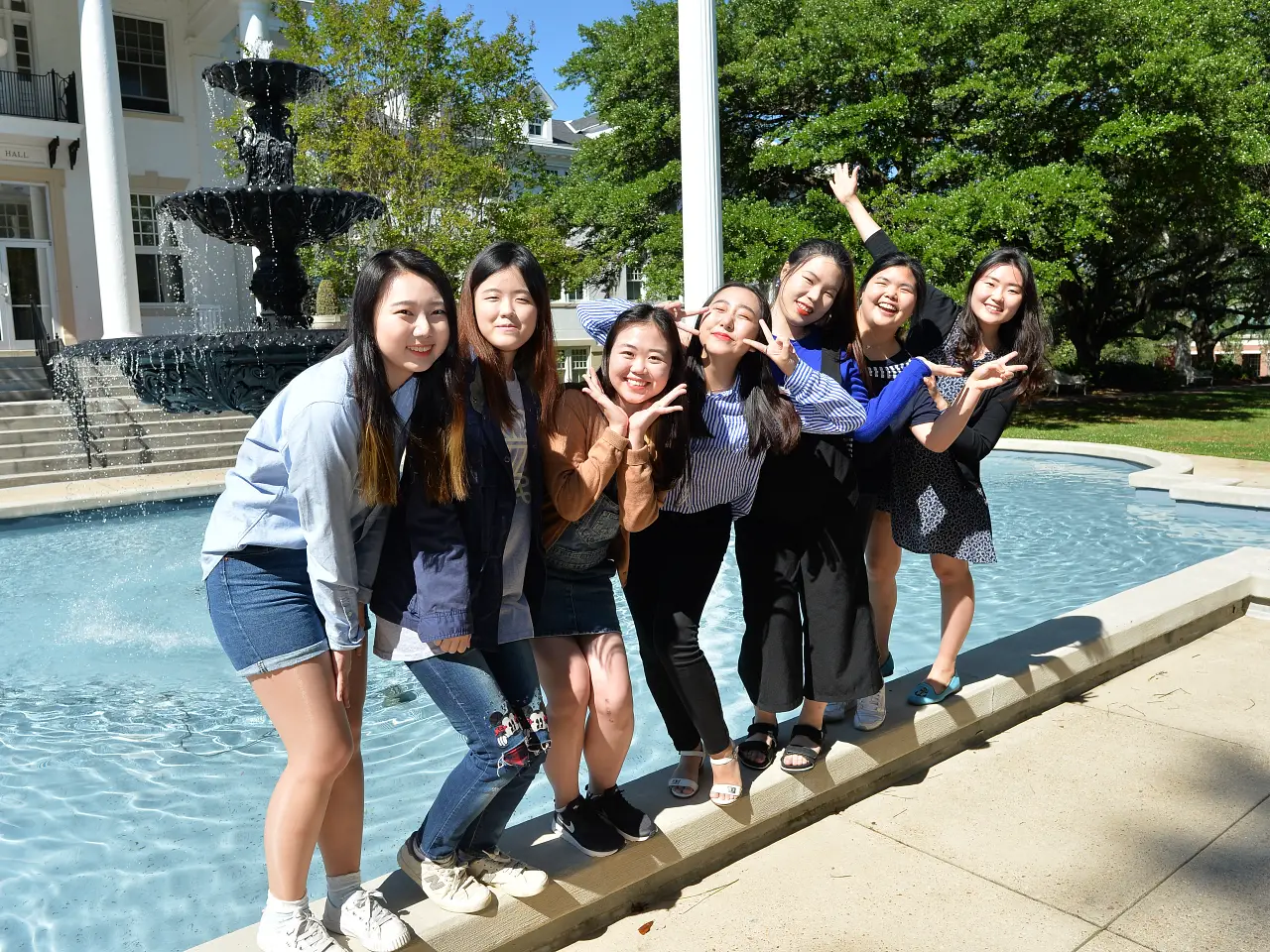 seven female students standing on the ledge of the fountain
