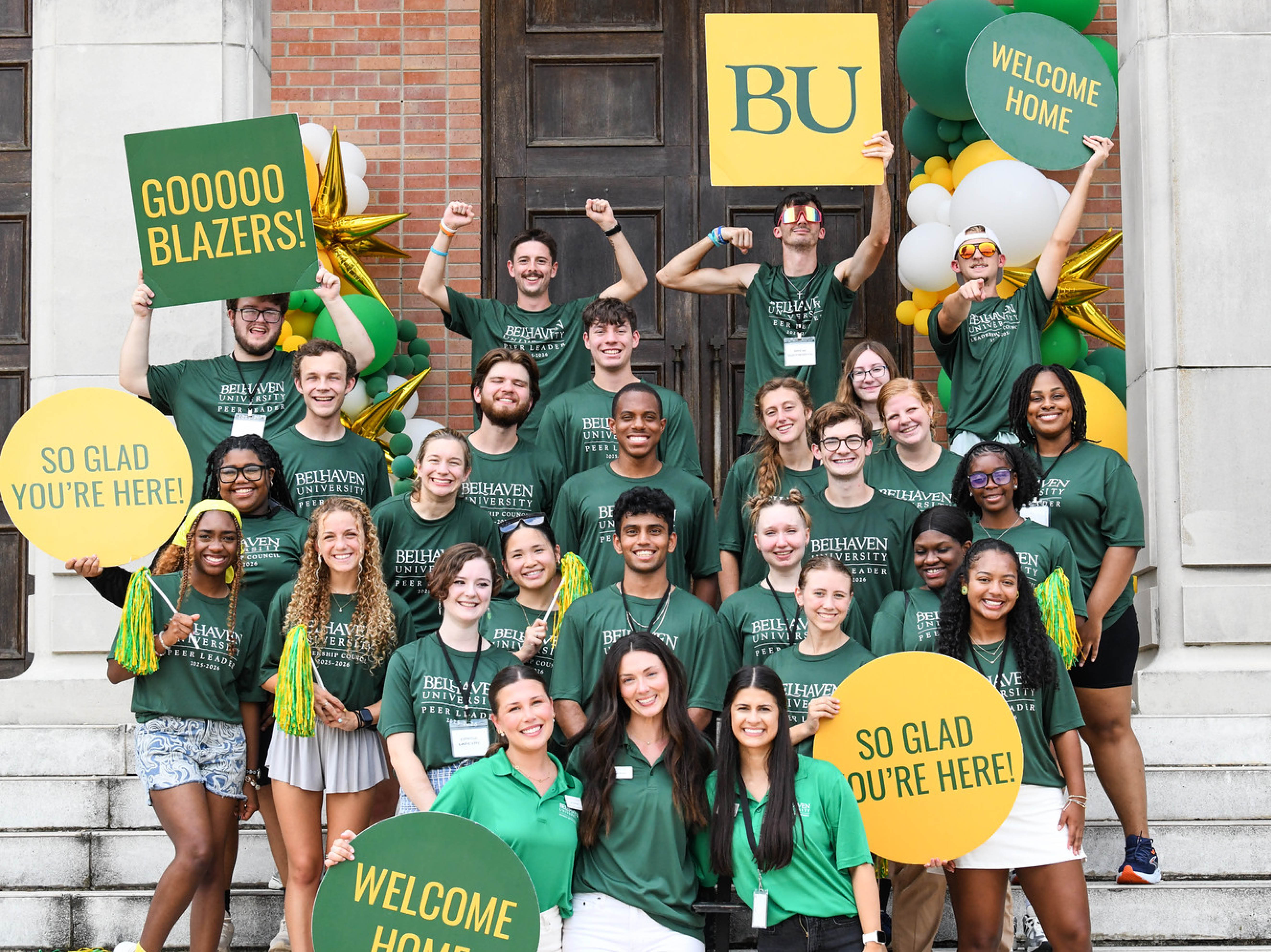 Group of student leaders in front of campus building welcoming students to campus