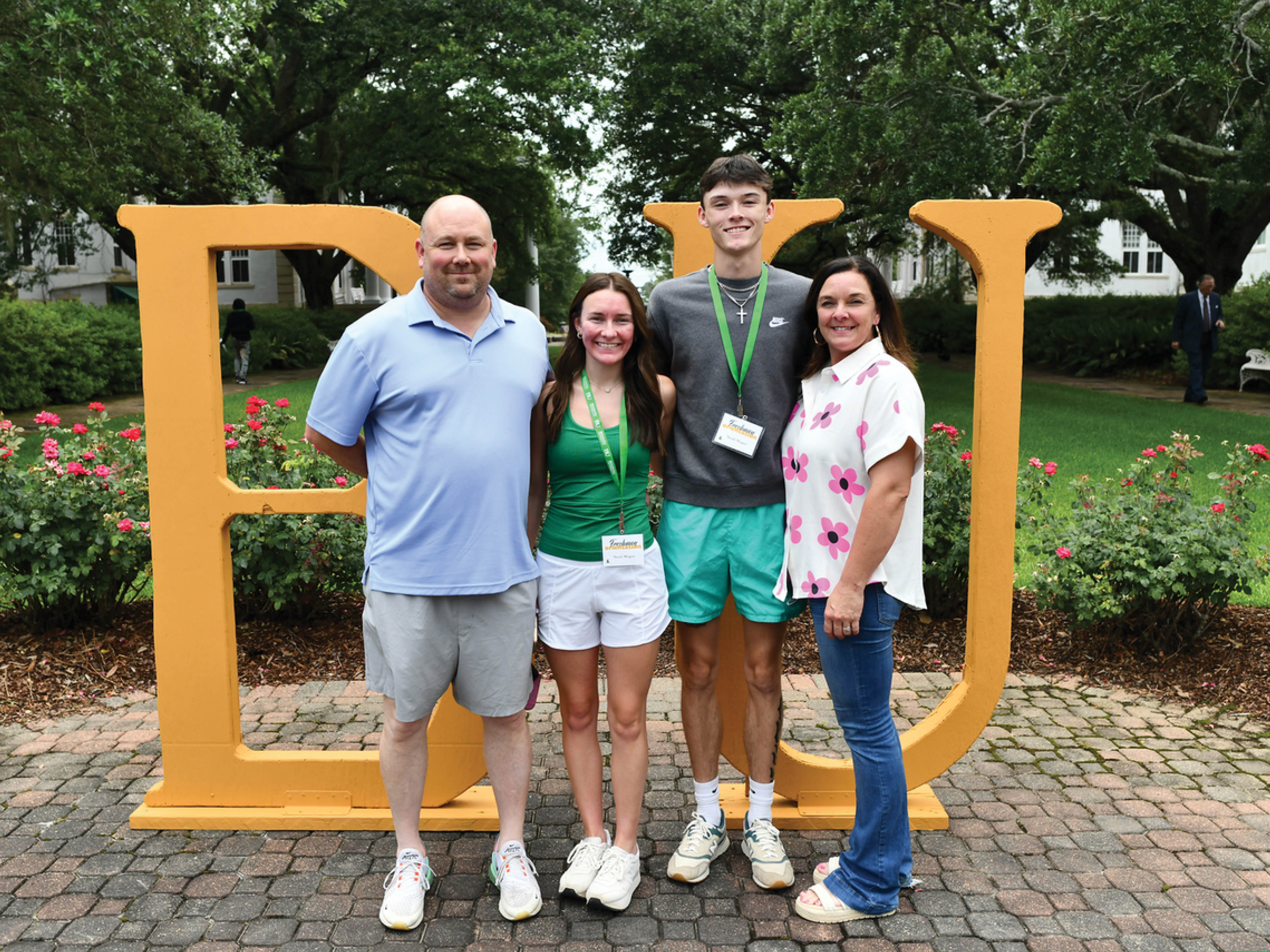 New family in in the center of campus smiling in front of BU sign