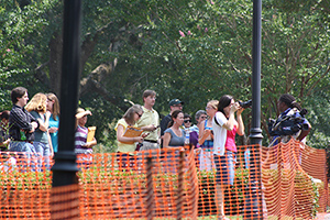 people behind an orange construction fence