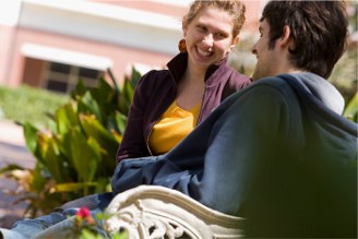 two students sitting on a bench in campus talking